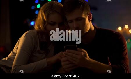 Happy couple using reading message on phone, ordering food online for Christmas Stock Photo