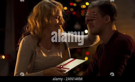 Caring lady giving her husband Xmas gift, pleasant surprise, holiday tradition Stock Photo