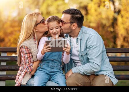 Happy family spending time together in the park.People,nature, and technology concept. Stock Photo