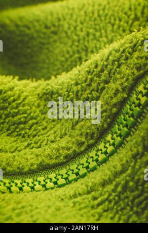 Close up shot of a YKK plastic zip fastener / zipper on fleece jacket. Metaphor keep mouth zipped, zipped lips, zipped file, green abstract. SEE NOTES Stock Photo