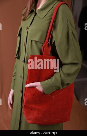 image of a female model wearing green dress shirt  and genuine red  leather shopper bag, cropped with no face, close up image for advertisment Stock Photo