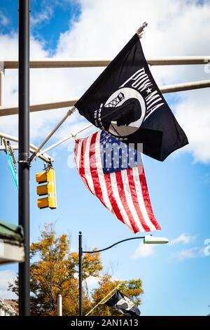 POW/MIA (Prisoners of War, Missing in Action) flag and American Flag wave high in the blue sky Stock Photo