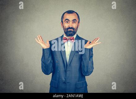 Ignorance and arrogance. Closeup portrait young man shrugging shoulders who cares so what I do not know gesture isolated on gray wall background. Huma Stock Photo