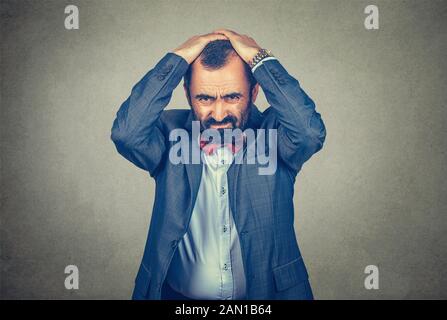 businessman holding hands on head in frustration, stressed man upset frustrated isolated on gray wall background. Negative human emotions Stock Photo
