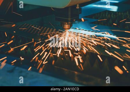 Machine for laser cutting of metal. Laser head cuts the sheet with a beam, sparks scatter in different directions Stock Photo