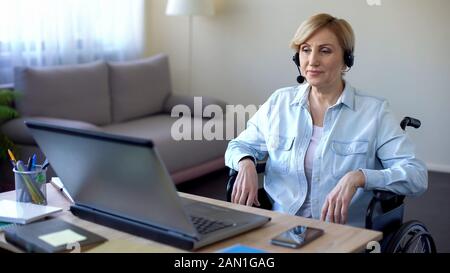 Call-center female operator in headphones talking with client, disabled woman Stock Photo