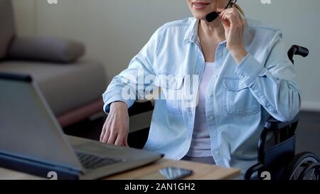 Disabled grandmother in headset talking with family online, video conference Stock Photo