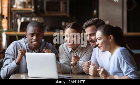 Excited diverse friends cheering watching match on laptop online Stock Photo