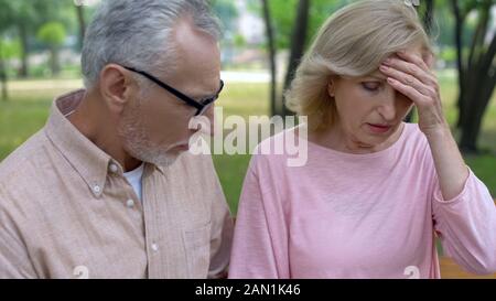 Old female suffering from migraine, caring husband supporting wife, health Stock Photo