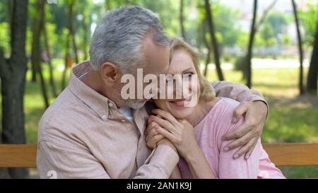 Happy senior couple embraces in park, man hugging woman, love until old age Stock Photo
