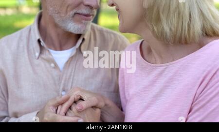 Loving elderly couple looking each other, man and woman holding hands, affection Stock Photo