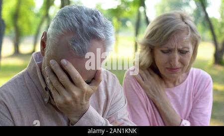 Mature couple crying sitting outdoors, incurable disease, retirement problem Stock Photo