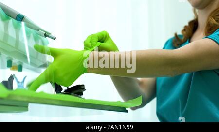 Lady dentist putting medical gloves on, modern equipment, high quality service Stock Photo