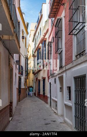 Colourful buildings line a narrow alley in Seville's historic Jewish Quarter.
