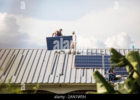 Team of electricians work to install solar panels on rooftop. Stock Photo