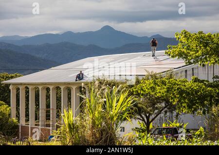 Two electricians work to install solar panels on roof. Stock Photo