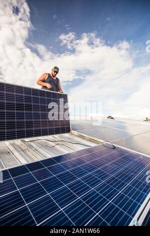 Low angle of electrician installing solar panels on roof. Stock Photo