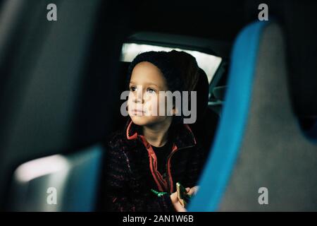 young boy sat in an electric car looking out the window Stock Photo