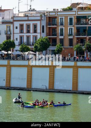 Kayakers, on a Kayak Seville tour, gather for a briefing with their tour guide on the Guadalquivir River by the Puente de Isabel II bridge. Stock Photo