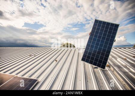 Low angle of hidden person carrying solar panel on roof. Stock Photo