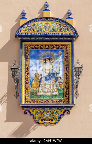 A colourful azulejos plaque of Saint Anne decorates the entrance to the Iglesia de Santa Ana, Seville's oldest parish church, which dates from 1276. Stock Photo