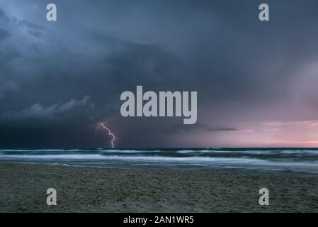 Lightning bolt from a thunderstorm over sea at sunset Stock Photo
