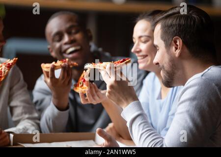 Overjoyed diverse colleagues eating tasty pizza laughing having fun Stock Photo