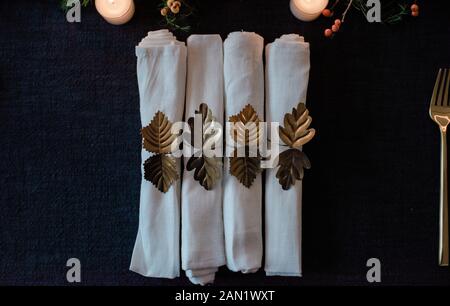 row of gold and white napkins on a decorated dinner table setting Stock Photo