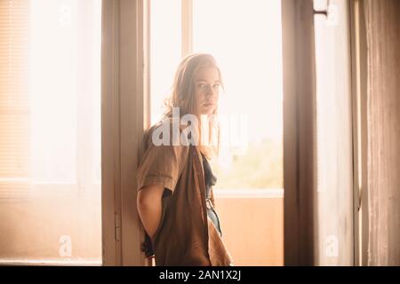 Young woman leaning on balcony doorway at home in summer Stock Photo