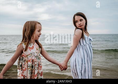 portrait of sisters holding hands and walking near a lake