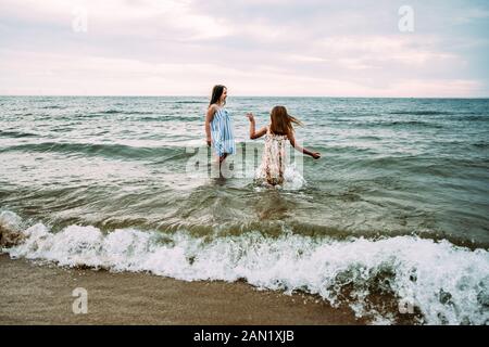 girls playing fully dressed in lake michigan on summer day