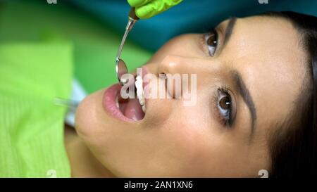 Professional dentist examining womans oral cavity with mirror, close-up Stock Photo