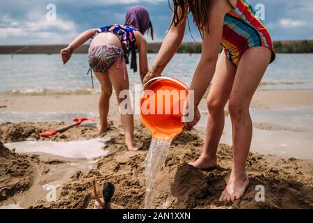 young children playing with water and sand at a lake