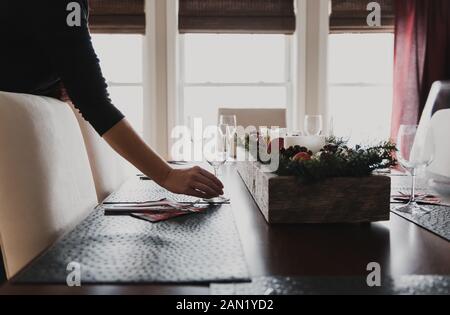 Close up of hand placing wine glass on place setting of dining table. Stock Photo