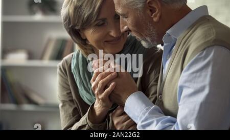 Elderly married couple looking at each other with tenderness and holding hands Stock Photo