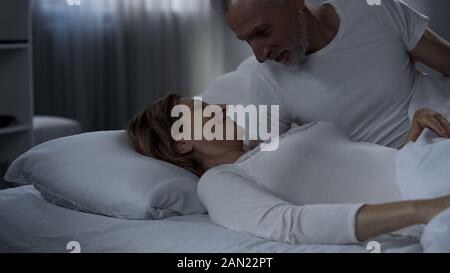 Retiree male and female lying in bed and smiling, happily married, tenderness Stock Photo