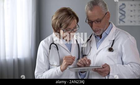 Therapists team looking at tablet, using modern app, technologies in medicine Stock Photo