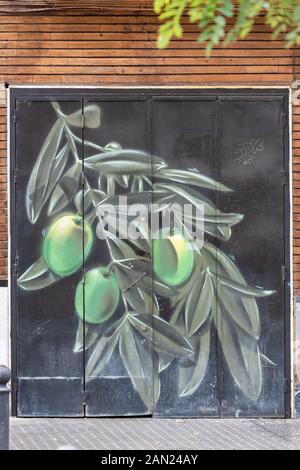 An olive branch with large green olives painted on the garage door of a building in Plaza San Juan de la Palma in Seville. Stock Photo