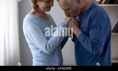 Senior man holding and kissing womans hands, lady flirting on date, attraction Stock Photo