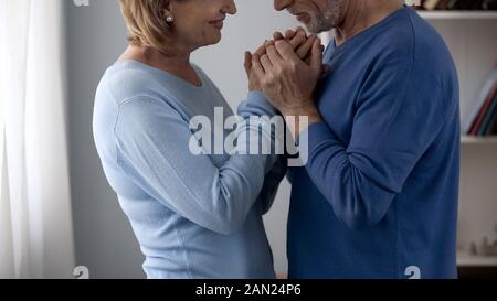 Retiree couple holding hands, looking at each other with love and gratefulness Stock Photo