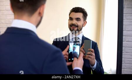 Cheerful manager in suit taking selfie in mirror reflection, social networking Stock Photo