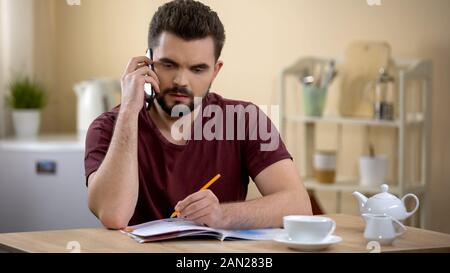 Male searching job offer, calling on magazine advertisement, celebrating success Stock Photo