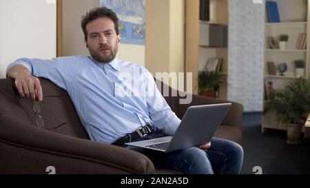 Freelance writer sitting with laptop at home, thinking about work issues Stock Photo