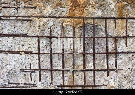 Old damaged and weathered concrete wall with iron rods. Stock Photo