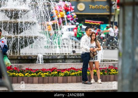 Hanoi, Vietnam - 11th October 2019: A young Asian couple taking photos next to a fountain in Hanoi, capital of Vietnam Stock Photo