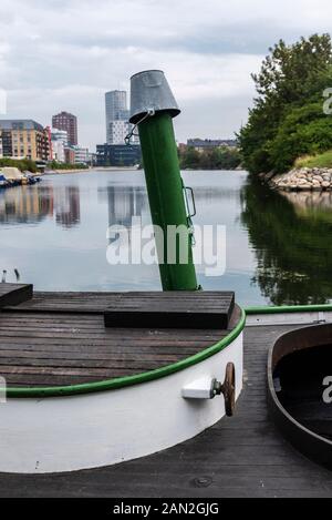 Pier with a boat with a bucket in Fiskehoddorna, traditional fish market on a street with the city of Malmo in the background in Sweden Stock Photo