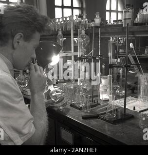 1950s, historical, male research scientist in a laboratory at Leeds University at a workbench using glass containers to mix chemicals. Stock Photo