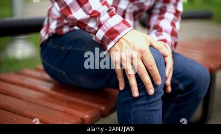 Man massaging painful knee, suffering from pain, injury after workout, trauma Stock Photo
