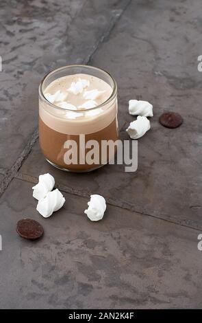 Cup of coffee with caramel topping and marshmallows on grey table. Stock Photo