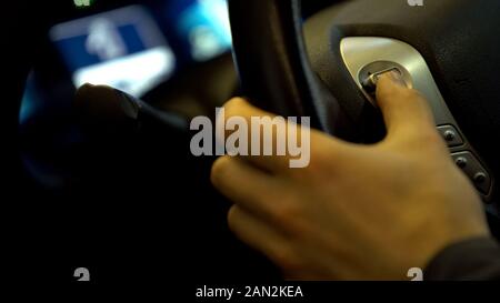 Driver hand pressing source button on steering wheel, testing modern automobile Stock Photo